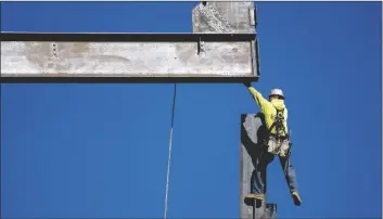  ?? AP PHOTO/MATT ROURKE ?? An ironworker guides a beam during constructi­on of a municipal building in Norristown, Pa., on Feb. 15.