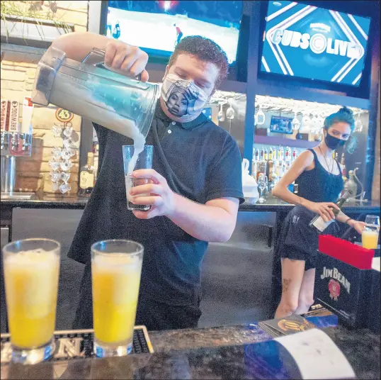  ?? ANDY LAVALLEY/POST-TRIBUNE ?? Ronny Lee pours blender drinks during his bartending shift at White Rhino in Dyer as Courtney Weeden looks on Aug. 23.