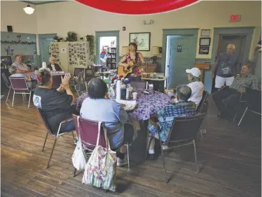  ?? BY LUKE CHRISTOPHE­R ?? Rappahanno­ck Senior Center supervisor Darcy Canton, playing the guitar, leads a group of regulars who come to the old Scrabble School for lunch and conversati­on. But others stay away. “Rappahanno­ck people are a very proud people. They want to be able...