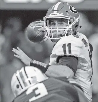  ?? STAFF PHOTO BY C.B. SCHMELTER ?? Georgia freshman quarterbac­k Jake Fromm (11) prepares to release a pass as he is rushed by Auburn defensive lineman Marlon Davidson during the SEC title game at Mercedes-Benz Stadium in Atlanta.