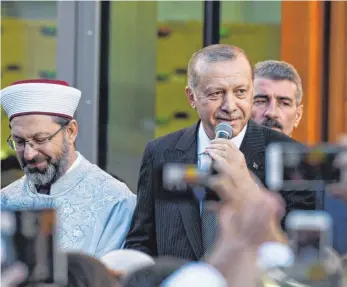  ?? FOTO: DPA ?? Der türkische Präsident Recep Tayyip Erdogan (Mitte) gab sich bei der Moschee-Eröffnung in Köln milde. Trotz des Andrangs vieler Menschen blieb es ruhig.