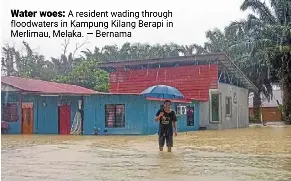  ?? — Bernama ?? Water woes: a resident wading through floodwater­s in Kampung Kilang Berapi in Merlimau, Melaka.