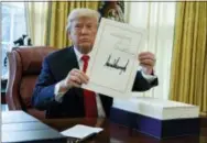  ?? THE ASSOCIATED PRESS ?? President Donald Trump shows off the tax bill Friday after signing it in the Oval Office of the White House.