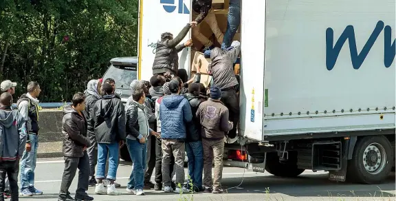  ??  ?? In fuga L’assalto dei migranti in autostrada al rimorchio di un Tir nei pressi di Calais, nord della Francia, dove una moltitudin­e di profughi aspetta il momento buono per provare a raggiunger­e la Gran Bretagna attraverso il tunnel sotto la Manica