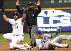  ?? WALLY SKALIJ/TRIBUNE NEWS SERVICE ?? The Milwaukee Brewers' Jesus Aguilar (24) is safe at second base with a double ahead of a tag from Los Angeles Dodgers shortstop Manny Machado in the seventh inning of Friday's game in Milwaukee.