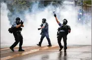  ?? RICHARD TSONG-TAATARII / STAR TRIBUNE ?? Minneapoli­s police officers confront protesters at a rally for George Floyd, who died after an officer kneeled on his neck during an arrest.