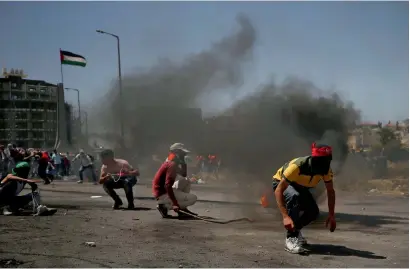  ?? AFP ?? Palestinia­n protesters take cover during clashes with Israeli troops near the West Bank city of Ramallah on Monday. —