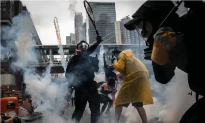  ??  ?? A protester uses a tennis racquet to hit back tear gas canisters during clashes with police after an anti-government rally in Hong Kong Photograph: Chris McGrath/Getty Images