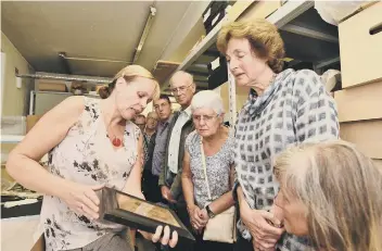  ??  ?? Glenys Wass, the collection­s manager at Peterborou­gh Museum showing visitors artifacts in the vaults.