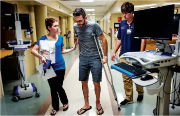  ?? STAFF PHOTOS BY DOUG STRICKLAND ?? Adam Bunger walks to his car Friday with the help of his fiancée, Sarah Jane Lewis, at Erlanger hospital after his hip made it too painful to sit in a wheelchair. His hip was broken when he was hit by a Ford pickup while riding his bicycle.