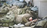  ?? STEFANI REYNOLDS / GETTY IMAGES FILES ?? Members of the National Guard sleep in the U.S. Capitol on Jan. 14 after security was increased in Washington following the breach of the U.S. Capitol the week before.