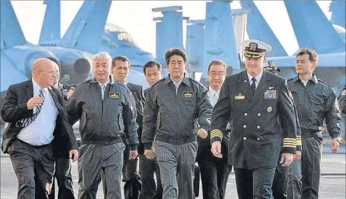  ?? JAPAN POOL / AFP ?? El primer ministro de Japón, Shinzo Abe (centro), y su ministro de Defensa, Nakatani (izquierda), visitando el portaavion­es nuclear Ronald Reagan el pasado día 18 en aguas niponas