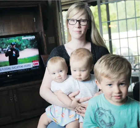  ?? DAX MELMER ?? Kendra Holtby and her three children — nine-month-old twins Jessa left, and Adalynn, and Tanner, 3 — closely watch the news coming out of Houston, Texas, while visiting her parents’ home in Belle River on Monday. The family, including husband and...