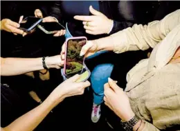  ?? ?? Audience members lock their phones in Yondr pouches at a comedy show. The pouches prevent people from using their phones, but the system isn’t foolproof.