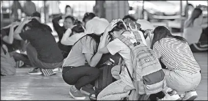  ?? MIGUEL DE GUZMAN ?? Students and faculty members duck and cover during an earthquake drill at the Pamantasan ng Lungsod ng Maynila last July 19.