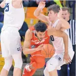  ?? ELI LUCERO/THE HERALD JOURNAL VIA AP ?? Tim Williams of New Mexico splits Utah State defenders Norbert Janicek (15) and Quinn Taylor (10) on Wednesday night.