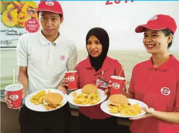  ?? PIC BY NORASIKIN DAINEH ?? Sugarbun staff presenting the Swinger Combo menu at an outlet in Kota Kinabalu recently. The local fast food brand is planning to open five more outlets later this year.