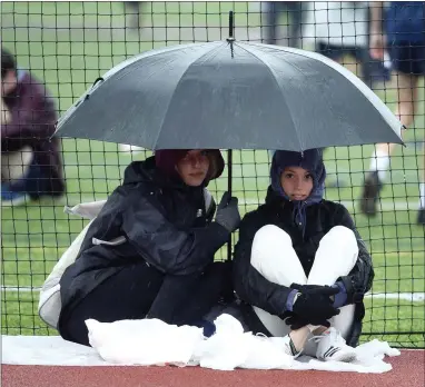  ?? PETE BANNAN — MEDIANEWS GROUP ?? It was a wet track at the Henderson Invitation­al Friday at Henderson High School but that didn’t stop the runners and field athletes including these girls running in the 1600meter race. Two athletes wait to compete in the high jump.