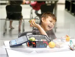  ?? AP Photo/LM Otero ?? ■ Bruce McCall, 5, laughs as he eats his lunch behind plastic barriers during martial arts daycare summer camp Tuesday at Legendary Blackbelt Academy in Richardson, Texas. As daycare and youth camps re-open in Texas, operators are following appropriat­e safety measures to ensure children stay safe from COVID-19.