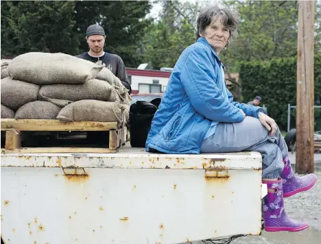  ?? NICK EAGLAND ?? Lynne Donesley sits on a flatbed truck loaded with sandbags, “supervisin­g” her son and grandson, as they help their neighbours protect their homes near Brockie Place and 14th Avenue, an area in Okanagan Falls that received evacuation orders Thursday...