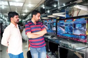  ?? — AFP ?? People watch a broadcast of Ishaq Dar presenting the budget at an electronic­s store in Karachi.