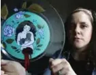  ??  ?? Artist Ashley MacLure holds her painting ‘The Dream’ created from acrylic paint and color marker on a glass plate, at her home in Milford, Mass.