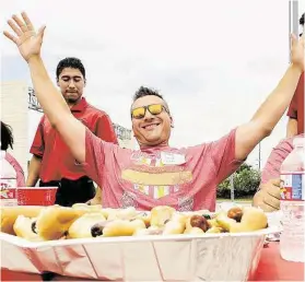  ?? Diana L. Porter photos / For the Chronicle ?? Firefighte­r Dan Goeke celebrates his win after eating eight hot dogs as he and fellow firefighte­rs took on local police at the first Firemen vs. Police Hot Dog Eating Contest to support the The 100 Club at Hub Hyundai West of Katy on on June 27.