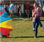  ?? Ana Ramirez ?? Alexis Swan runs with Kinley Marchand during a parachute race during the 18th annual Children’s Festival hosted by the Cynthia Woods Mitchell Pavilion and ExxonMobil. Children enjoyed indoor and outdoor activities including arts and crafts and kite...