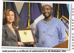  ??  ?? Joshi presents a certificat­e of achievemen­t to Ali Abubakar, who was honored as safest cabbie on the city streets.