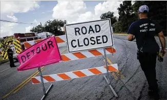  ?? NICK WAGNER / AMERICAN-STATESMAN ?? A Bastrop County firefighte­r passes a barrier that blocks access to the site of an oil spill in the 400 block of FM 20 on Thursday. Evacuation­s were ordered for people living within a mile radius of the spill, and a shelter was establishe­d at River...