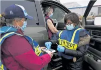  ??  ?? Becca Arndt, left, and Christy Deem, right, prepare to administer a COVID-19 vaccine to Betty Hadden of Red Mesa at a site in Durango.