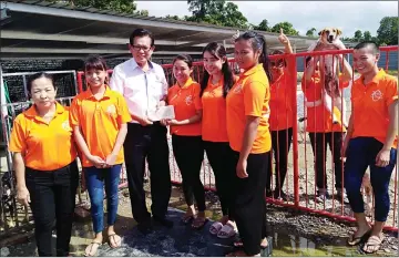  ??  ?? Lee hands over the cheque to Kho (fourth left) as ZSM volunteers look on at ZSM’s temporary shelter in Kuala Baram yesterday.