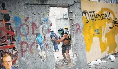  ?? Ariana Cubillos / Associated Press ?? An anti-government demonstrat­or destroys a wall to release pieces of concrete to throw at Venezuelan police during a protest Friday in Caracas.