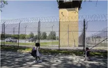  ?? AP ?? Myla Martinez, 6 (left), and sister Jaliyah Santiago, 4, pass by a guard tower as they leave Logan Correction­al Center after visiting their mother, Crystal Martinez, in an Illinois prison.