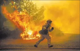  ?? Noah Berger ?? The Associated Press A firefighte­r runs July 31 while trying to save a home as a wildfire tears through Lakeport, Calif.