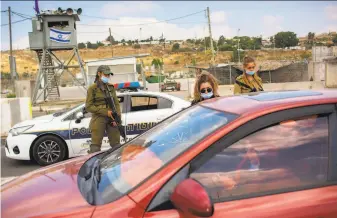  ?? Oded Balilty / Associated Press 2020 ?? Israeli soldiers check Palestinia­n IDs in June near the West Bank city of Nablus. The nation’s premier human rights group is adopting a term long seen as taboo even by many critics of Israel.