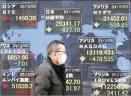  ?? ?? A man walks past a stock quotation board at a brokerage in Tokyo.