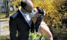  ?? (MICHAEL WARGO VIA AP) ?? In this April 11, 2020, photo provided by Michael Wargo, newlyweds Danielle Cartaxo and Ryan Cignarella kiss while wearing masks after getting married in West Orange, N.J.