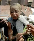  ?? AP ?? A dazed child is passed from hand to hand after being rescued from a collapsed building in Lagos.