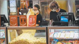  ?? KEITH SRAKOCIC/AP ?? AMC Theatres workers in western Pennsylvan­ia stock bins with popcorn Thursday as the movie venue reopened for the first time since the start of the coronaviru­s pandemic.