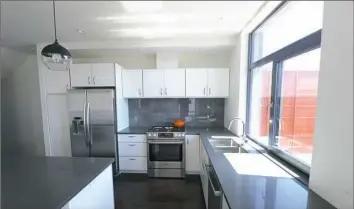  ?? Nate Guidry/Post-Gazette photos ?? Left: The kitchen has quartz counter tops, a drawer-style microwave and an electric stove. (Gas is not permitted in Passive House due to the fumes). Right: A view from one of the bedrooms.