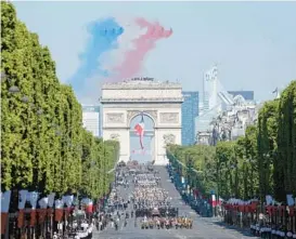  ?? LUDOVIC MARIN/GETTY-AFP ?? The jets of an elite French flying team release smoke in the colors of the French flag Thursday during a flyover of the Bastille Day military parade in Paris.