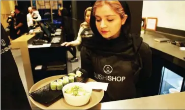  ?? ATTA KENARE/AFP ?? A waitress takes a plate of sushi from the kitchen at a high-end French sushi chain that opened the previous week in northern Tehran on Sunday.