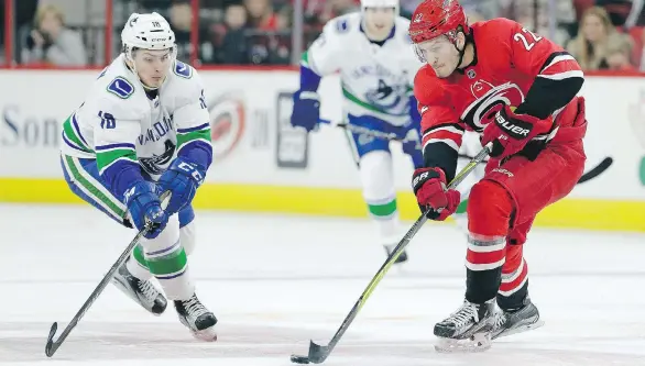  ?? GERRY BROOME/THE ASSOCIATED PRESS ?? Canuck Jake Virtanen and the Carolina Hurricanes’ Brett Pesce chase the puck during the first period of Friday’s game in Raleigh, N.C. Pesce sniped the first goal of the game after a defensive zone breakdown by Vancouver left him wide open in the top...