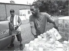  ?? Associated Press ?? In this Aug. 11 photo, Shawn Jones, right, and Tony Price, distribute bottled water at a point of distributi­on at Saint Mark Missionary Baptist Church.