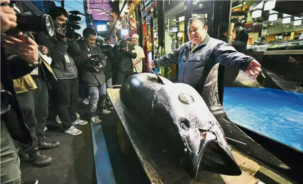  ??  ?? Catch of the day: Kimura (right) showing off the prized bluefin tuna he had bought at the annual New Year auction while standing in front of his Sushi Zanmai restaurant in Tokyo.