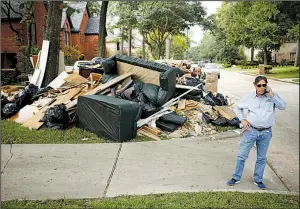  ?? Bloomberg file photo ?? Constructi­on company owner Frank Jones talks on a cellphone next to debris from a house in Spring, Texas, that was flooded after Hurricane Harvey in September 2017. A bill to overhaul the Federal Emergency Management Agency’s flood insurance program has been stalled in Congress since November.