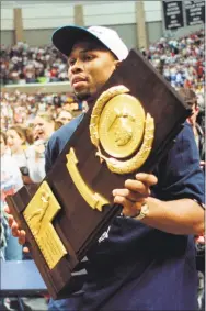  ?? Associated Press file photo ?? UConn co-captain Ricky Moore carries the winner's trophy during a rally for the team on the UConn campus in 1999.