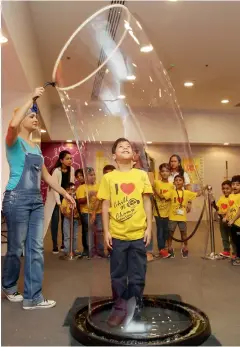  ??  ?? BUBBLING HIGH.. An enthusiast­ic boy standing still during a bubble experiment done by one of the trainers at the Science Party.