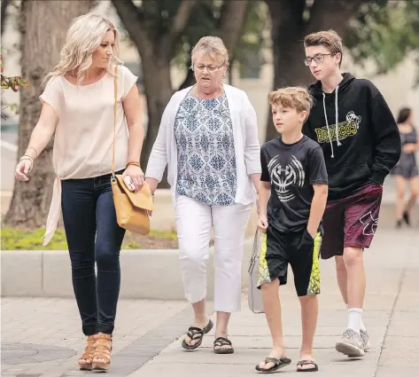  ?? LIAM RICHARDS/THE CANADIAN PRESS ?? Christina Haugan, wife of deceased coach Darcy Haugan, leads her two sons Jackson, 9, and Carson, 13, into a court hearing in Saskatoon on Wednesday related to money raised following the Humboldt Broncos bus crash.